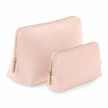 Two BG751 pouches by Bagbase, featuring a minimalist design in beige with gold zippers and slightly textured surfaces, are displayed in different sizes. They are set against a plain white background.