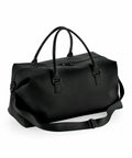 A Bagbase BG760, a black duffel bag equipped with handles and an adjustable shoulder strap, features a zippered main compartment.