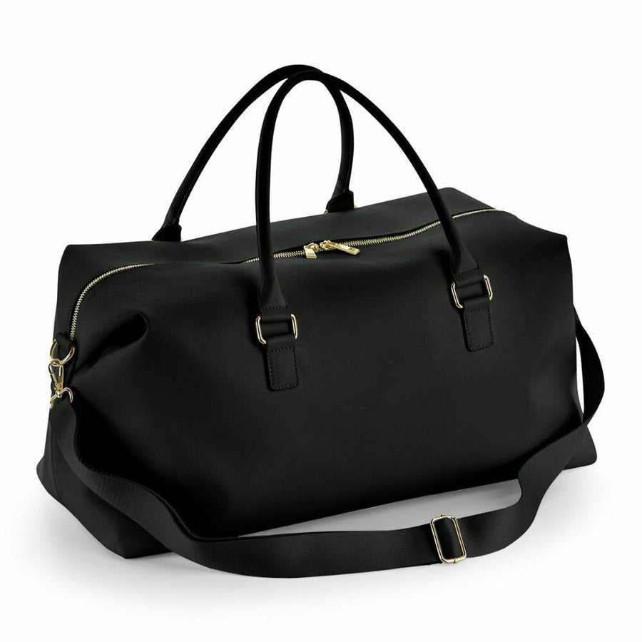 The Bagbase BG760 is a black leather duffel bag featuring gold zippers and a detachable shoulder strap.
