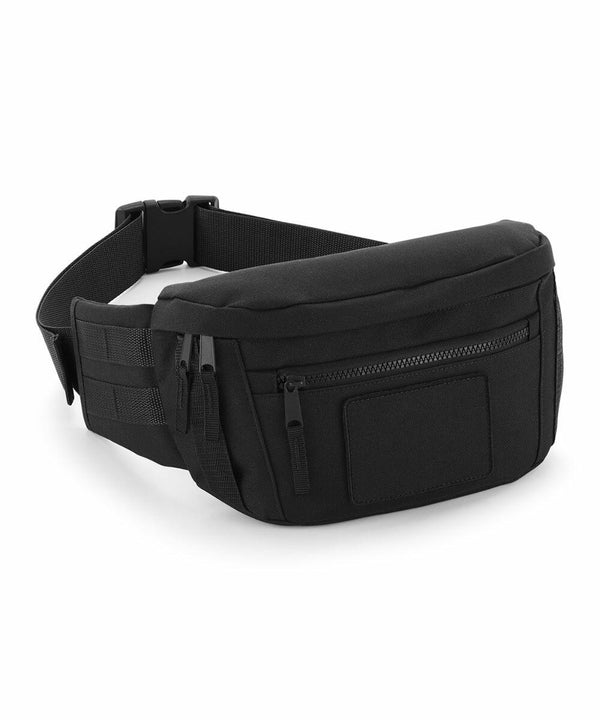 A black waist bag with several zippered compartments, including one on the front. It has an adjustable strap and a plastic buckle for closure. The Bagbase BG842 features a sleek, minimalist design and appears to be made of durable fabric.