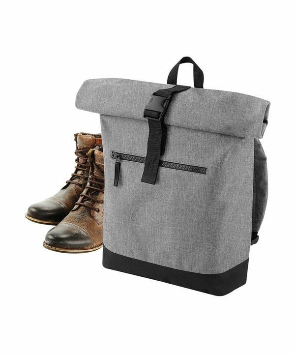 A pair of worn brown leather lace-up boots is placed near a grey Bagbase BG855 with black zipper and buckle closures against a white background. The Bagbase BG855 has a front zip pocket and a black bottom.