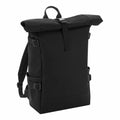 The Bagbase BG858 is a black roll-top backpack featuring adjustable shoulder straps and side buckles, designed to stand upright.