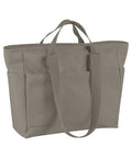The Bags canvas tote is large and taupe, featuring two short handles, two long shoulder straps, exterior side pockets, and a simple, functional design.