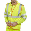 A person is zipping up a bright yellow high-visibility safety vest with reflective silver stripes over a matching long-sleeve shirt. The vest has an orange trim and a clear plastic pocket on the left chest area. This is the Beeswift BS061.