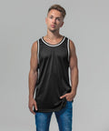 A man with short hair is standing with a neutral expression, wearing a sleeveless black shirt with white trim and blue jeans. The background is plain and light gray. He is wearing the BY009 by Build Your Brand.