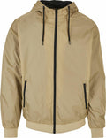 Introducing the BY016 jacket from Build Your Brand: a stylish beige hooded design with sleek black zippers and adjustable drawstrings. This versatile piece features two front pockets, along with elasticated cuffs and hem for a comfortable fit.