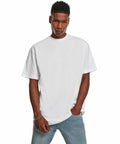 A person in a Build Your Brand BY122 T-shirt and blue jeans stands with one hand in a pocket, posing against a plain white background.