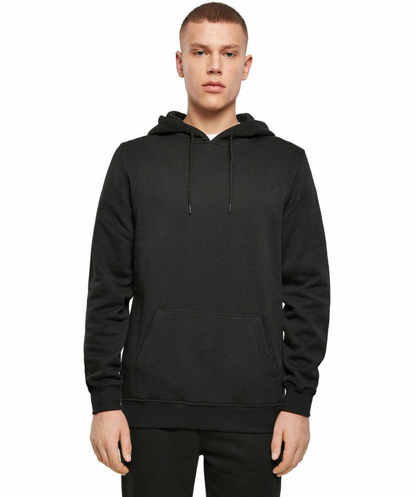 A person standing and facing forward, wearing a plain black BY137 hoodie and black pants from Build Your Brand against a white background.
