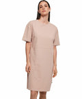 A person is posing in a plain, short-sleeved, knee-length, beige dress from Build Your Brand called the BY181.
