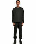 Person wearing a black long-sleeve shirt and black pants from Build Your Brand, standing against a plain white backdrop in the BY198.