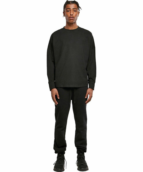Person wearing a black long-sleeve shirt and black pants from Build Your Brand, standing against a plain white backdrop in the BY198.