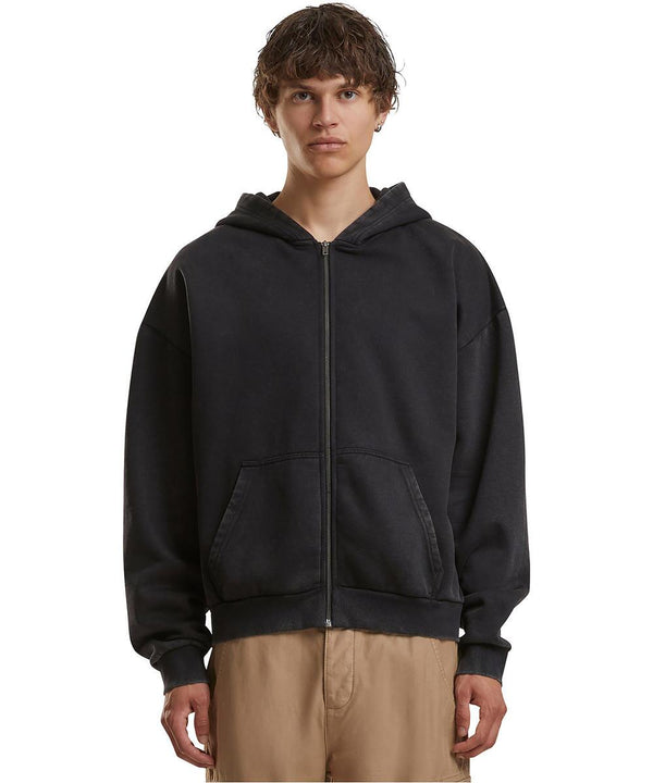 A person with short, wavy hair wears the Build Your Brand Vintage Heavy Zip Hoodie in black and khaki trousers, standing facing forwards against a plain white background.