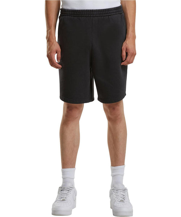 A person is seen from the waist down wearing Build Your Brand Vintage heavy sweatshorts, paired with a white vest, white socks, and white trainers while standing facing forwards with arms relaxed at their sides.