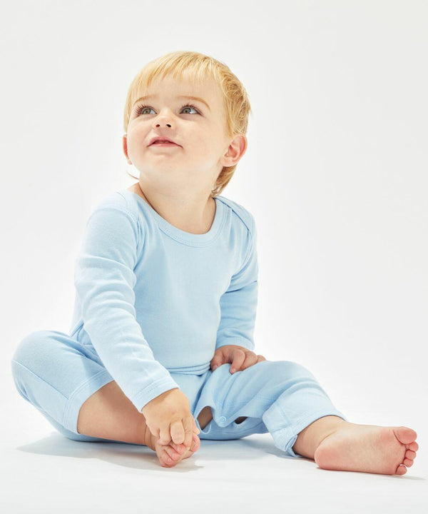A baby with light hair, wearing a Babybugz BZ013 light blue onesie, is sitting on the floor against a plain white background, looking upward.