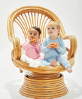 Two toddlers in pastel pajamas sit in a rattan chair, each holding a Babybugz BZ067. They are looking upward with neutral expressions.