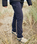 Person wearing dark Craghoppers CR234 outdoor pants and hiking shoes walking on a sandy path through tall grass.