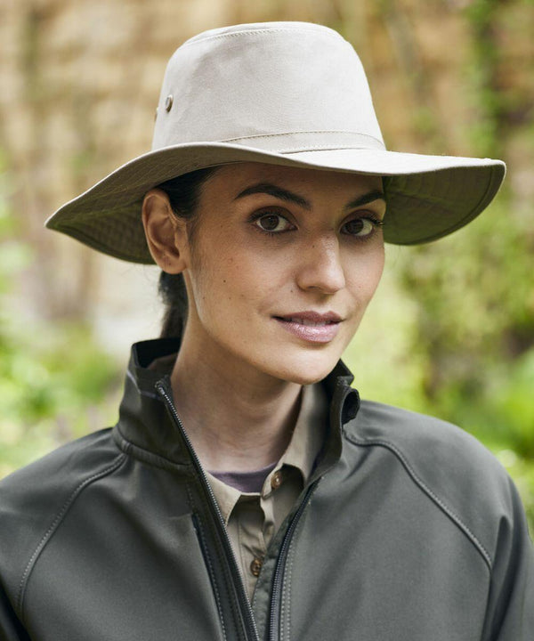 Woman wearing a Craghoppers CR601 wide-brimmed hat and dark jacket, outdoors with a natural background.