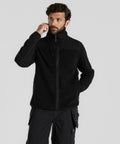 A man wearing a black Craghoppers CR703 fleece jacket and black cargo pants stands against a plain background, touching his ear with one hand.