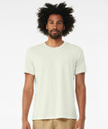 A man with an afro hairstyle wears a plain, light-colored Bella + Canvas CV001 T-shirt and beige pants. He stands against a plain white background, looking directly at the camera.