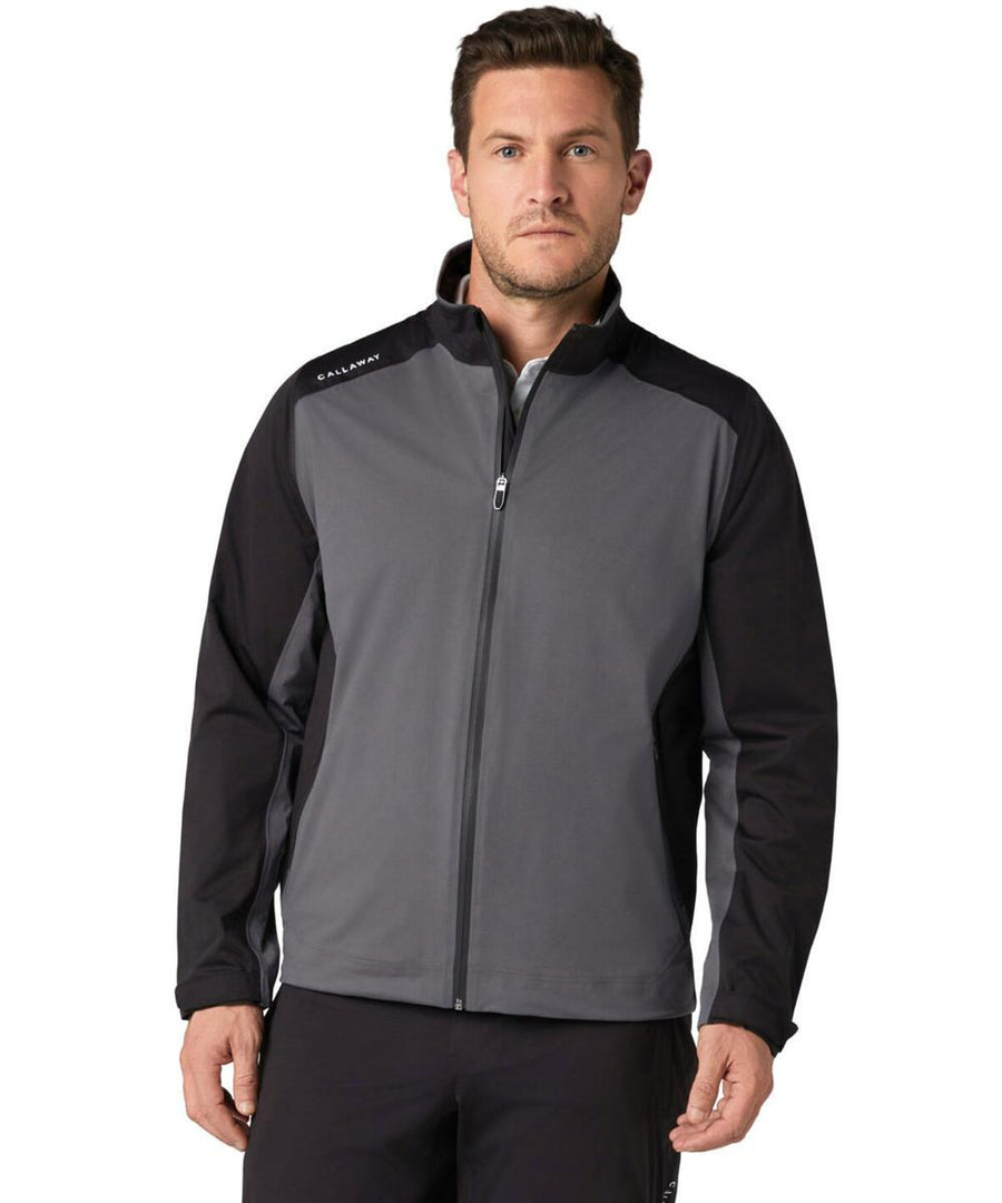 A man stands facing forward in a grey and black Callaway Stormlite III jacket with a stand-up collar and "Callaway" on the left shoulder, paired with black trousers.
