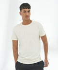 A person with short hair is wearing an AWDis Ecologie EA001 and black pants, standing against a white background.