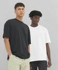 Two men are standing against a plain background, one in an EA006 by AWDis Ecologie black t-shirt and light pants, the other in an EA006 by AWDis Ecologie white t-shirt and dark pants.