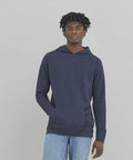 A person with short, curly hair wearing an AWDis Ecologie EA040 navy blue hoodie and light blue jeans stands against a plain gray background.