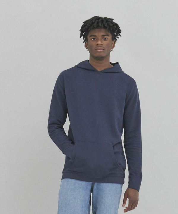 A person with short, curly hair wearing an AWDis Ecologie EA040 navy blue hoodie and light blue jeans stands against a plain gray background.