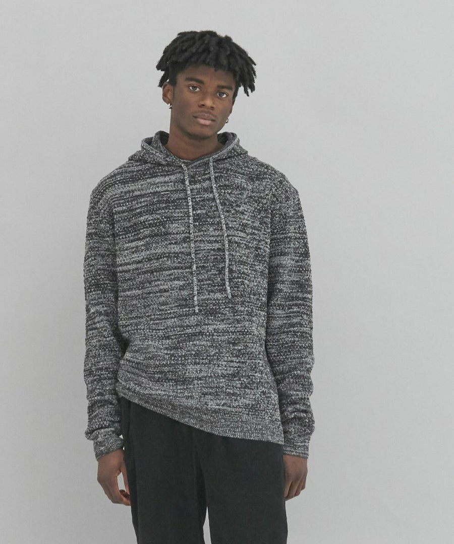 A man with short curly hair wearing an AWDis Ecologie EA080 and black pants stands against a plain, light grey background.