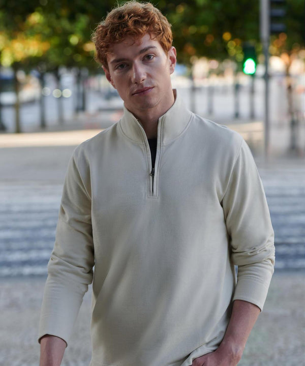 A young man with short curly red hair is wearing the Front Row Premium piqué 1/4-zip top in light beige, standing outdoors near trees and a road with green and red traffic lights blurred in the background.