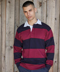 A person in a Front Row FR08M long-sleeved rugby shirt with horizontal maroon and navy stripes stands in front of a wooden wall.