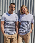 A man and woman wearing Front Row FR135 white and blue striped T-shirts and beige pants stand side by side against a corrugated metal background.