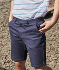 A person wearing a Front Row FR605 striped shirt and navy blue shorts stands with hands in pockets on a rocky surface.
