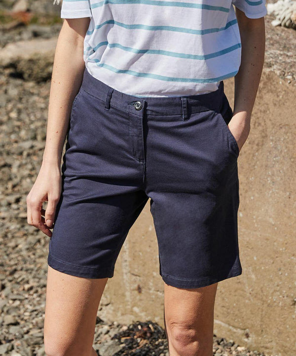 Person wearing a blue and white striped shirt and navy shorts from Front Row's FR606 collection with hands in pockets, standing outdoors on a rocky surface.
