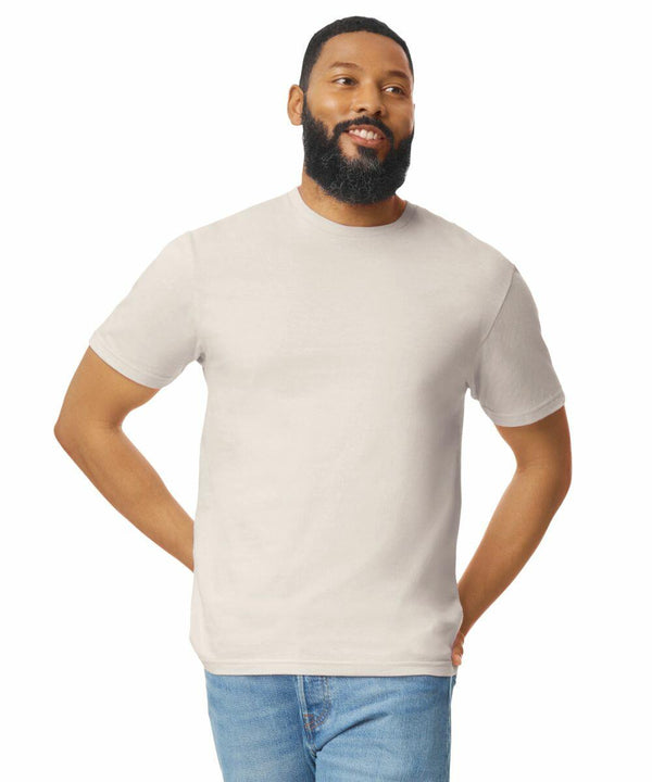 A man with a beard wearing a plain white t-shirt (GD001 by Gildan) and blue jeans stands with his hands behind his back, looking off to the side.