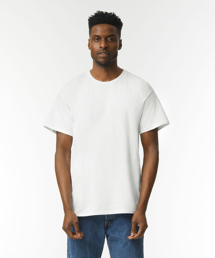Man wearing a Gildan GD002 plain white T-shirt and blue jeans standing against a plain white background.