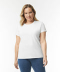 A person with shoulder-length blonde hair wearing a plain white Gildan GD006 T-shirt and blue jeans stands against a white background.