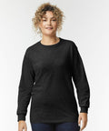 Person wearing a black GD014 long-sleeve shirt by Gildan and blue jeans, standing against a plain white background.