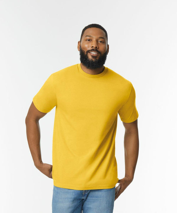 A man with a beard is wearing a Gildan GD024 yellow t-shirt and blue jeans, standing against a plain white background.