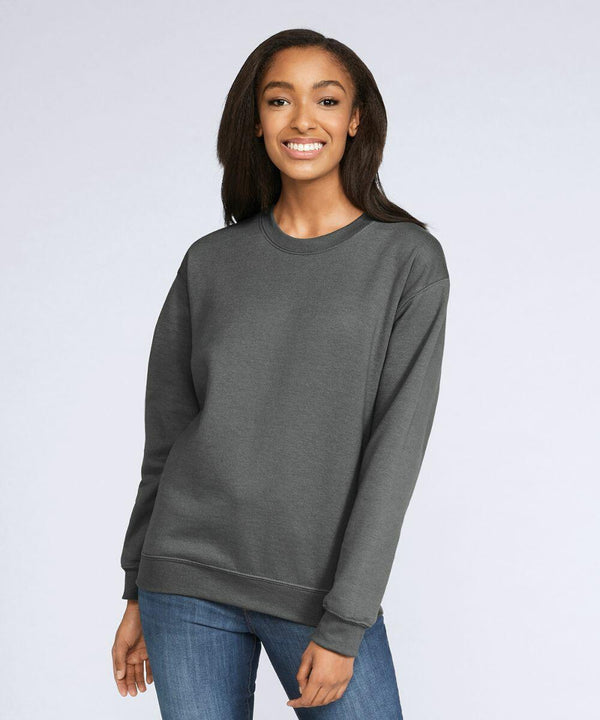 A person wearing a dark grey GD066 sweatshirt by Gildan and blue jeans stands smiling against a plain background.