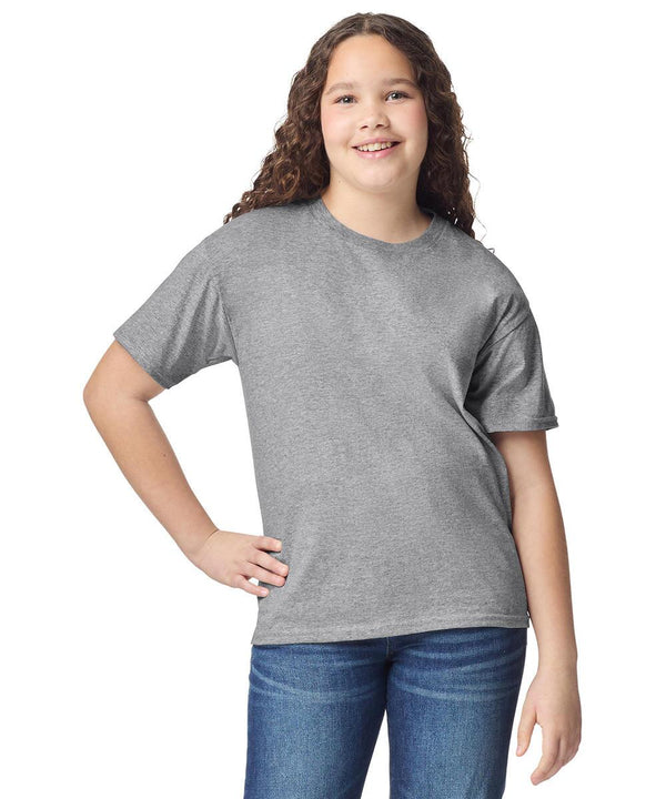 A smiling youth with long curly hair poses against a white background, wearing the Gildan light cotton youth t-shirt in grey and blue jeans, with one hand on their hip.