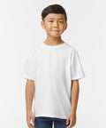 A young boy stands facing the camera, wearing a Gildan GD24B plain white T-shirt and blue jeans against a plain white background.