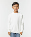 A young boy is standing and wearing a Gildan GD56B sweatshirt and blue jeans against a plain white background.