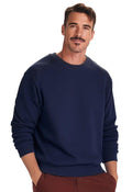 A man with short dark hair and a mustache is wearing a Uneek Adult Eco sweatshirt and brown pants, standing against a plain white background.