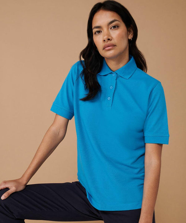 A person with long dark hair wears a Henbury HB401 bright blue short-sleeve polo shirt and black pants, posed against a neutral background.