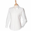 The Henbury HB511 is showcased on a wooden mannequin torso, featuring a classic collar and cuffed sleeves in a white long-sleeve button-up design.