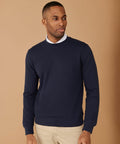 A man in a Henbury HB840 and beige pants stands against a plain brown background.