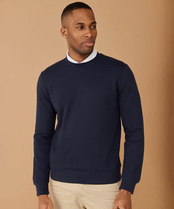 A man in a Henbury HB840 and beige pants stands against a plain brown background.