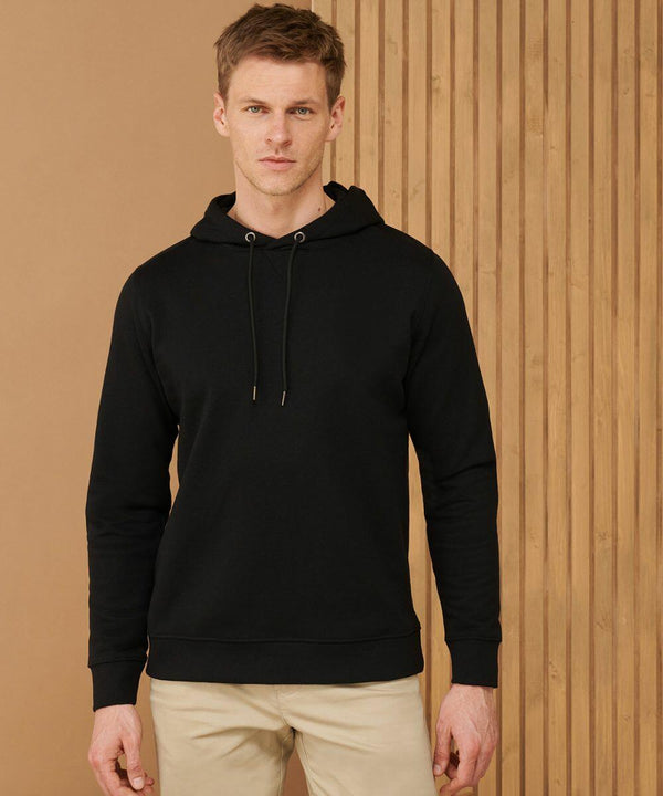 A man wearing a black Henbury HB841 hoodie and beige pants stands in front of a wooden panel background.