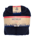 A navy blue accessories set with a blanket and eye mask is folded and wrapped in packaging labelled "Accessories," featuring a blue city skyline on a tan and red background.